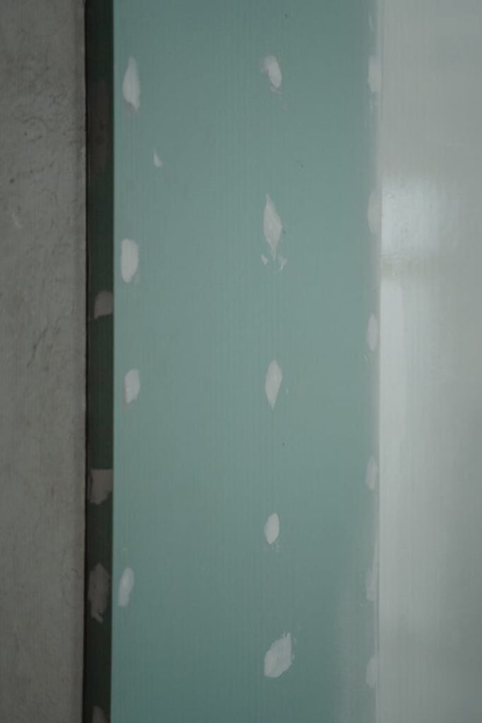Mastering the First Impression: Your intriguing post title goes here Freshly installed green drywall with white patches, ready for painting or finishing touches in home renovation.