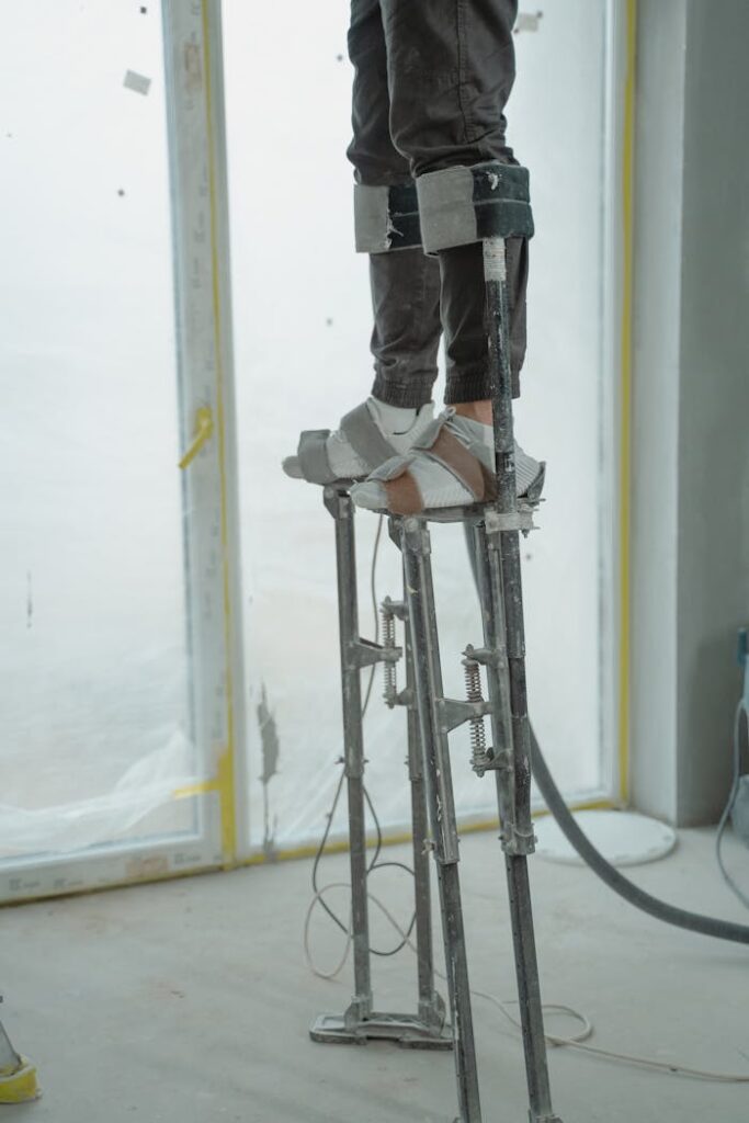 The Art of Drawing Readers In: Your attractive post title goes here Worker on stilts adjusting high areas in a room under renovation.